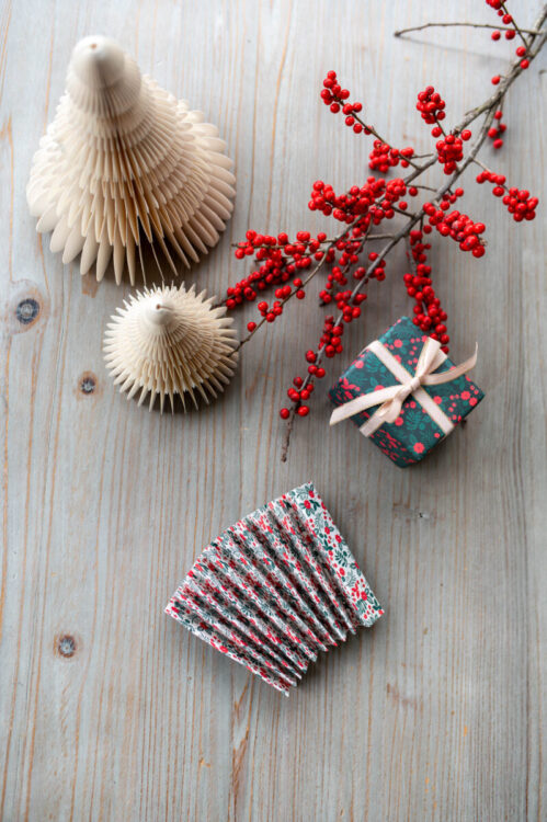 Beautiful handmade paper star garland Christmas decoration process image made using Lucy says I do double sided Christmas wrapping paper styled with Christmas berries and a little wrapped gift tied with ribbon