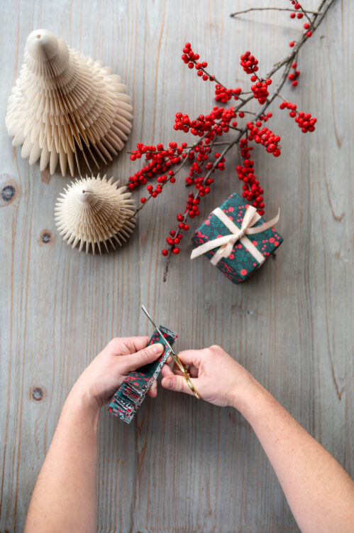 Beautiful handmade paper star garland Christmas decoration DIY made with Lucy says I do double sided Christmas wrapping paper styled with Christmas berries and a little wrapped gift tied with ribbon plus glue pot