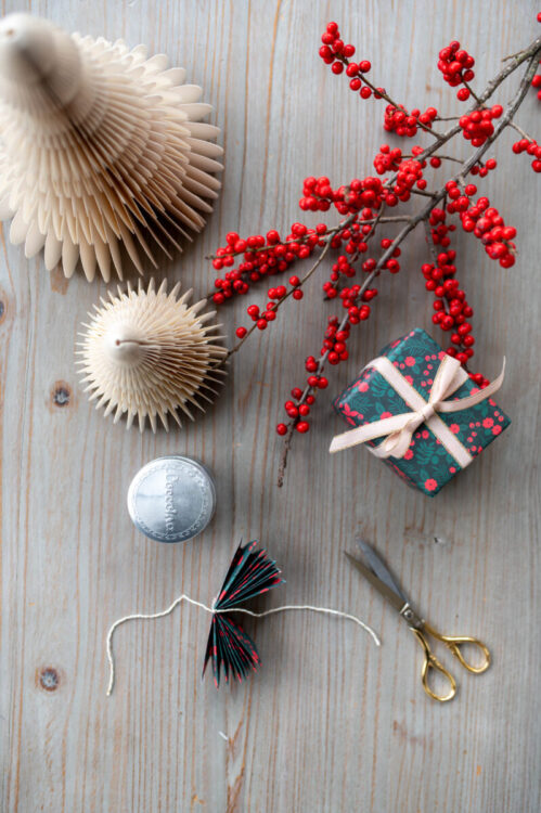 Beautiful handmade paper star garland Christmas decoration DIY made with Lucy says I do double sided Christmas wrapping paper styled with Christmas berries and a little wrapped gift tied with ribbon, and paper trees plus glue pot