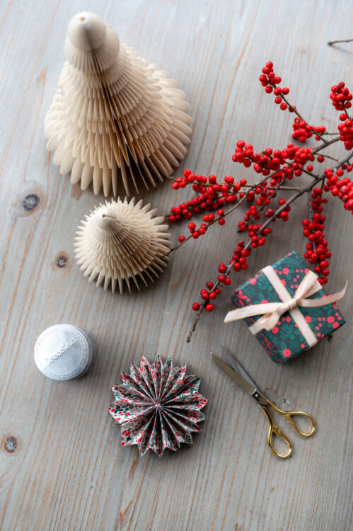 Beautiful handmade paper star garland Christmas decoration DIY made with Lucy says I do double sided Christmas wrapping paper styled with Christmas berries and a little wrapped gift tied with ribbon, and paper trees plus glue pot