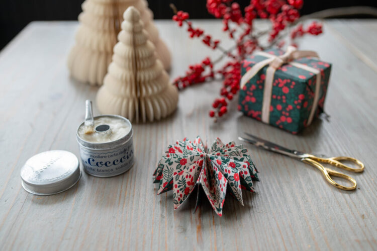 Beautiful handmade paper star garland Christmas decoration DIY made with Lucy says I do double sided Christmas wrapping paper styled with Christmas berries and a little wrapped gift tied with ribbon, and paper trees plus glue pot